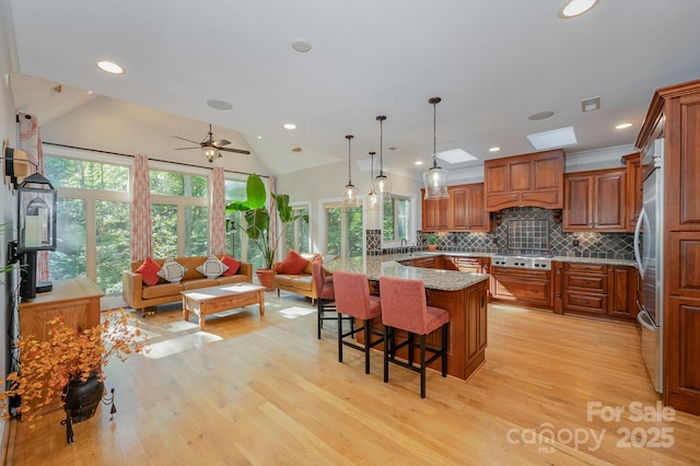 kitchen featuring custom range hood, a breakfast bar area, open floor plan, light stone countertops, and pendant lighting