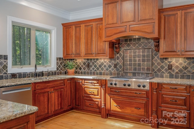 kitchen with light stone countertops, stainless steel appliances, light wood-style floors, ornamental molding, and decorative backsplash