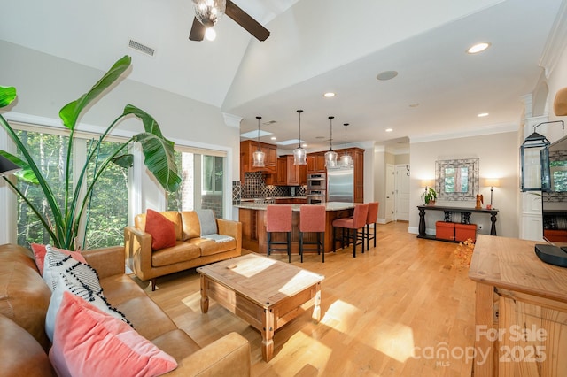 living area featuring visible vents, lofted ceiling, ornamental molding, light wood-type flooring, and recessed lighting