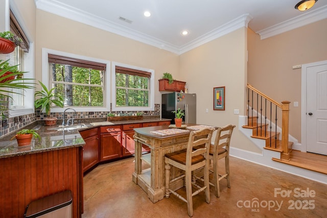 kitchen featuring a sink, backsplash, stainless steel fridge, and visible vents