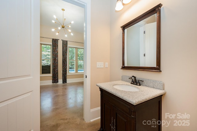 bathroom featuring vanity, baseboards, and an inviting chandelier