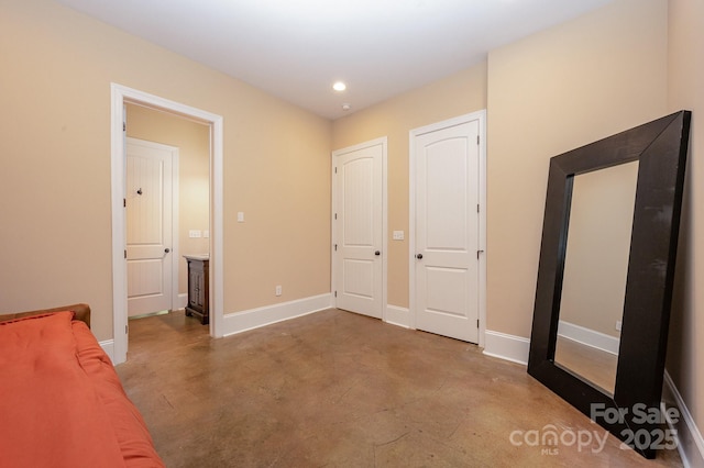 unfurnished bedroom with concrete floors, baseboards, and recessed lighting