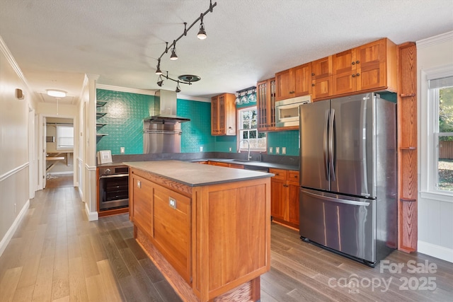 kitchen with ornamental molding, a center island, stainless steel appliances, and wall chimney exhaust hood