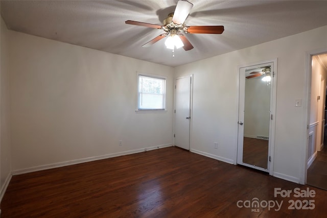 unfurnished bedroom featuring ceiling fan, dark wood-type flooring, and a textured ceiling