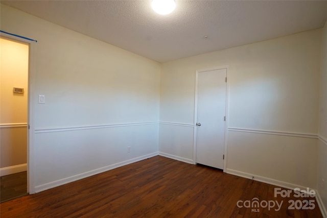 spare room featuring dark hardwood / wood-style floors and a textured ceiling