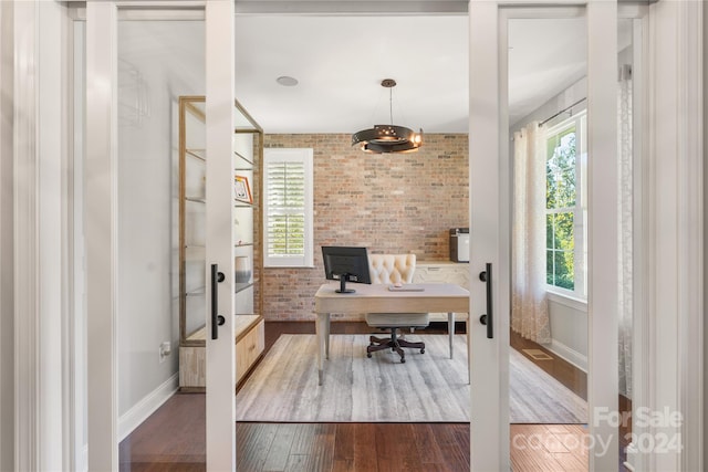 office space with brick wall and hardwood / wood-style flooring