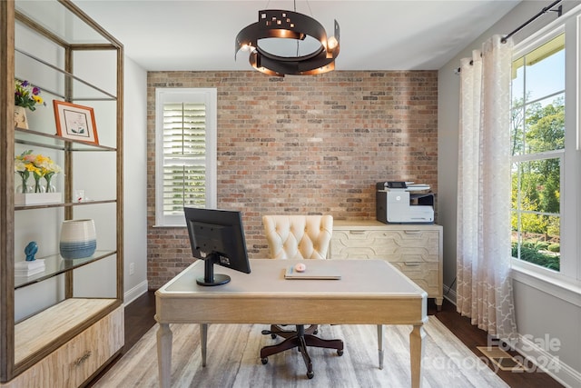 office with wood-type flooring and brick wall