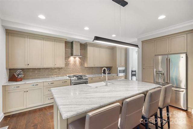 kitchen featuring wall chimney exhaust hood, cream cabinets, premium appliances, and dark hardwood / wood-style flooring