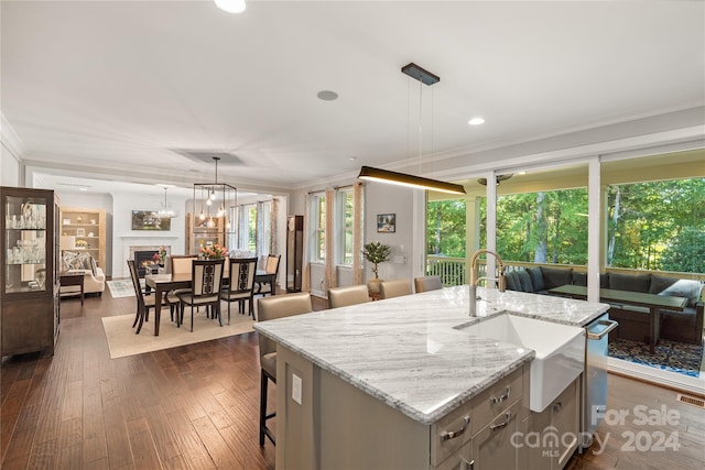 kitchen featuring dark wood-type flooring, decorative light fixtures, and a center island with sink