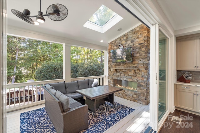 sunroom featuring an outdoor stone fireplace and vaulted ceiling