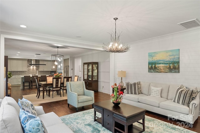 living room featuring crown molding, an inviting chandelier, and dark hardwood / wood-style floors