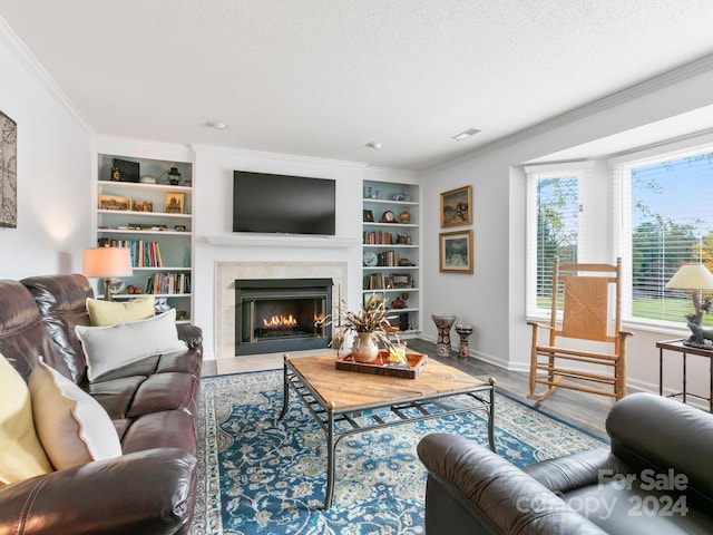 living room with built in shelves, crown molding, wood-type flooring, and a textured ceiling