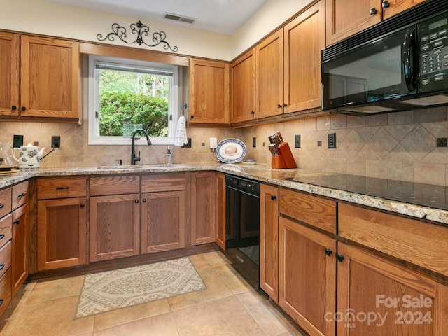 kitchen featuring black appliances, light tile patterned flooring, light stone counters, and sink