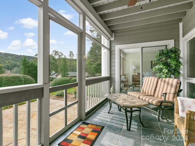 sunroom / solarium with beam ceiling, ceiling fan, and plenty of natural light