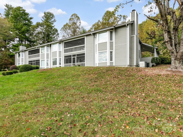 exterior space with a sunroom, a yard, and central AC