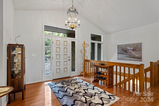 foyer entrance with lofted ceiling, hardwood / wood-style floors, and a chandelier