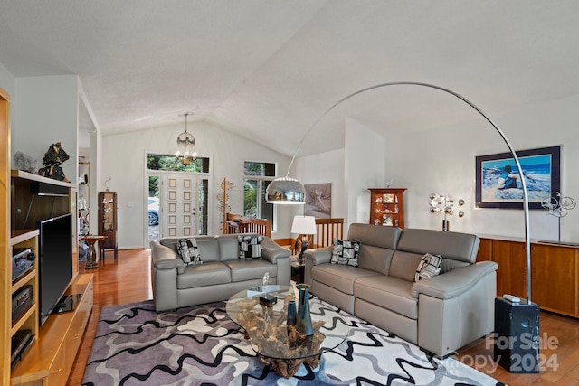 living room featuring wood-type flooring, lofted ceiling, and a chandelier