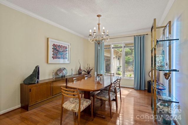 dining space with a textured ceiling, ornamental molding, an inviting chandelier, and light wood-type flooring