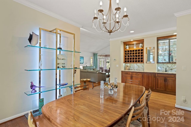 dining room featuring an inviting chandelier, lofted ceiling, crown molding, and light wood-type flooring