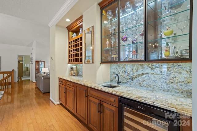 bar featuring beverage cooler, light stone countertops, light hardwood / wood-style flooring, crown molding, and sink