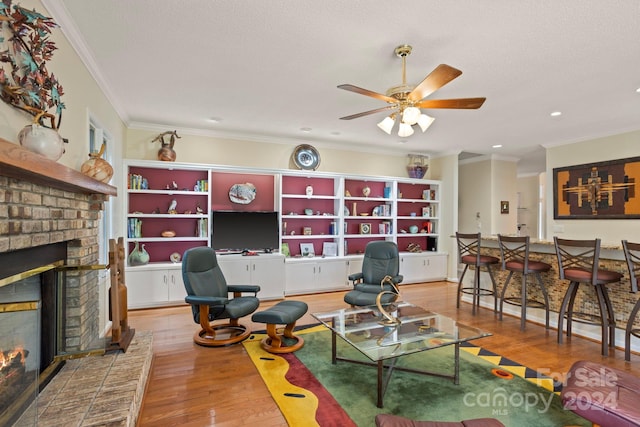 living room featuring a fireplace, a textured ceiling, ceiling fan, hardwood / wood-style flooring, and ornamental molding