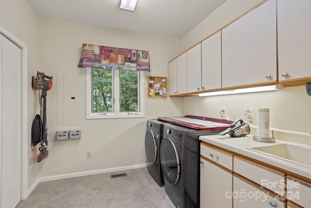 washroom with cabinets, a textured ceiling, and washer and clothes dryer