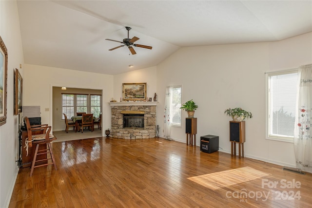 living room featuring ceiling fan, a stone fireplace, lofted ceiling, and hardwood / wood-style floors