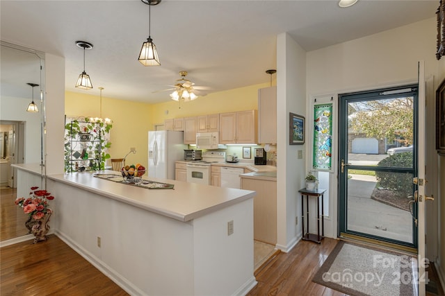 kitchen featuring hardwood / wood-style floors, ceiling fan with notable chandelier, pendant lighting, and white appliances