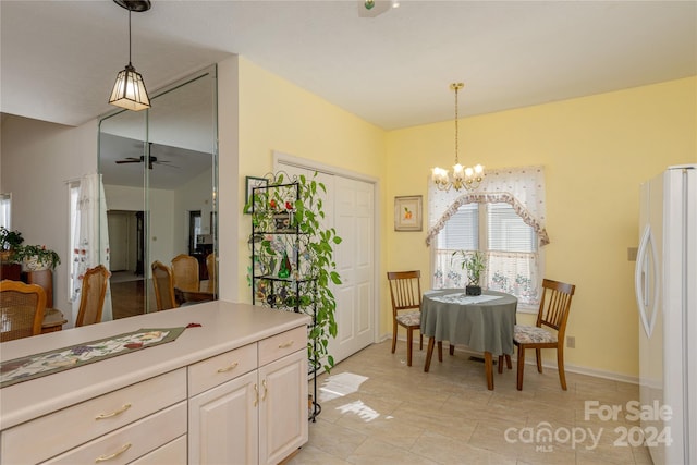 kitchen featuring white fridge, pendant lighting, ceiling fan with notable chandelier, and light tile patterned floors