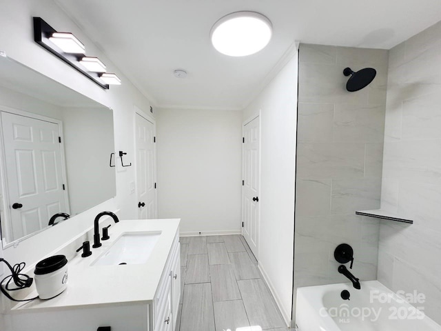 bathroom with ornamental molding, vanity, and tiled shower / bath