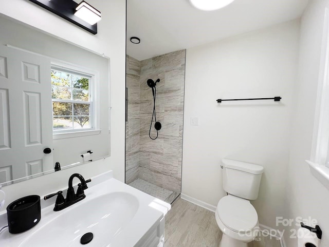 bathroom with sink, toilet, a tile shower, and hardwood / wood-style floors