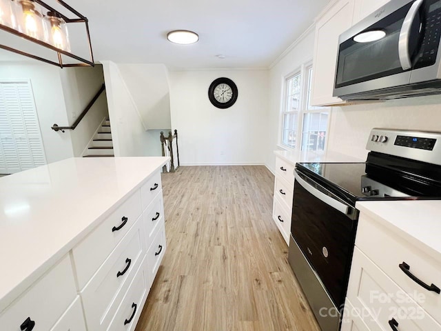 kitchen featuring white cabinets, appliances with stainless steel finishes, crown molding, and light hardwood / wood-style flooring