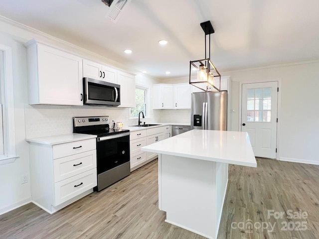 kitchen with light wood-type flooring, a center island, stainless steel appliances, white cabinets, and pendant lighting