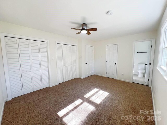 unfurnished bedroom featuring carpet, two closets, ceiling fan, and ensuite bath