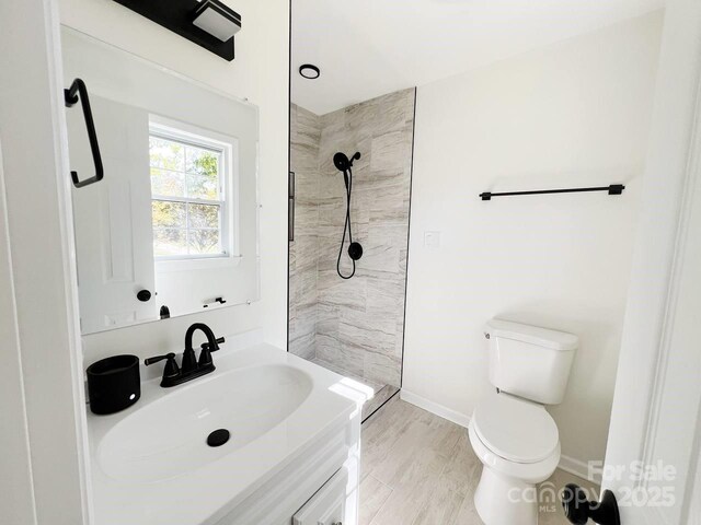 bathroom featuring vanity, a tile shower, and toilet