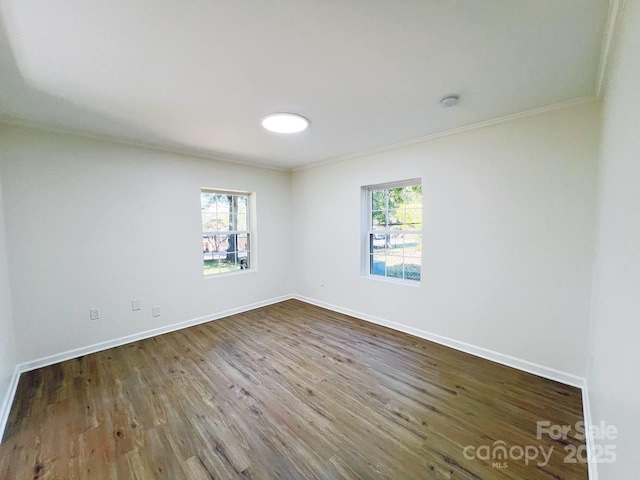 empty room featuring a healthy amount of sunlight, hardwood / wood-style flooring, and ornamental molding