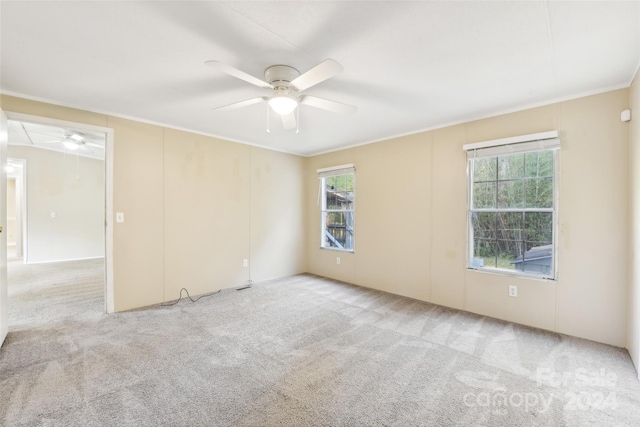 empty room featuring a wealth of natural light, crown molding, light colored carpet, and ceiling fan