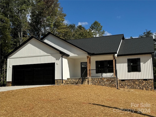 modern inspired farmhouse featuring covered porch and a garage