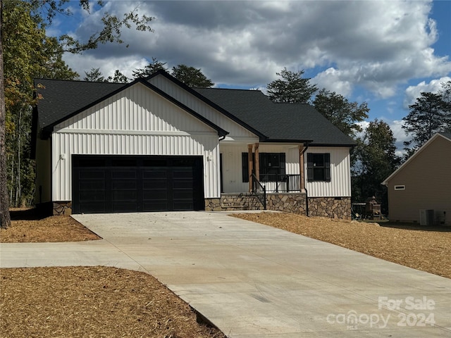 modern inspired farmhouse with central air condition unit, covered porch, and a garage