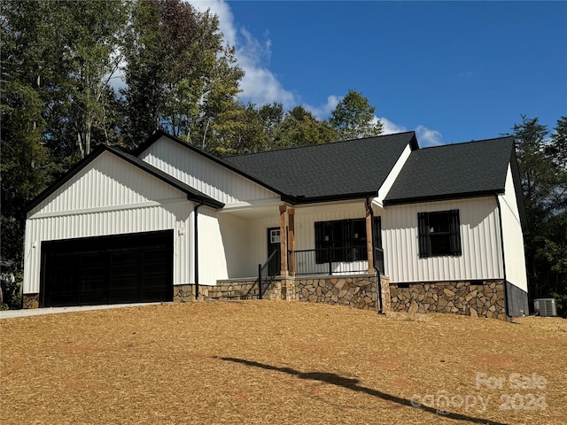 modern farmhouse style home with cooling unit, covered porch, and a garage