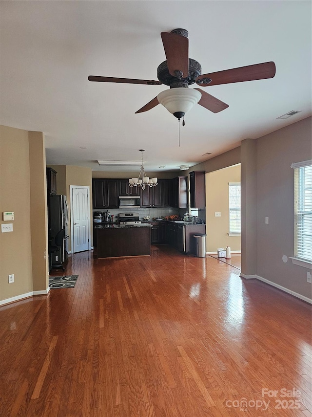 unfurnished living room featuring ceiling fan with notable chandelier and hardwood / wood-style floors