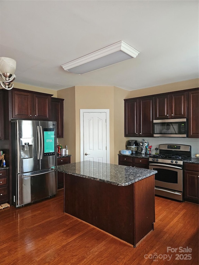 kitchen featuring stainless steel appliances, dark hardwood / wood-style floors, dark stone countertops, a kitchen island, and dark brown cabinetry