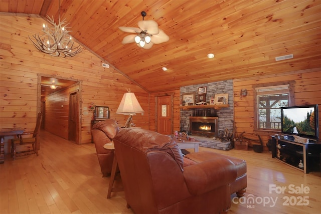 living room featuring lofted ceiling, wood ceiling, wooden walls, a fireplace, and light hardwood / wood-style floors