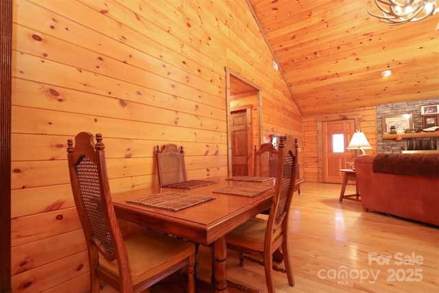 dining space with lofted ceiling, wooden walls, light wood-type flooring, and wooden ceiling