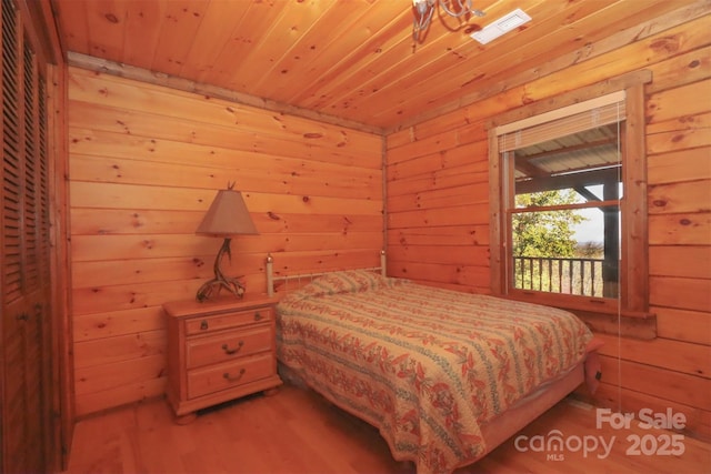 bedroom with wood-type flooring, wooden walls, and wood ceiling