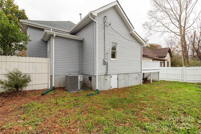 back of property with a yard and central AC