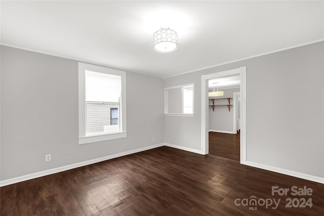 spare room with ornamental molding and dark wood-type flooring