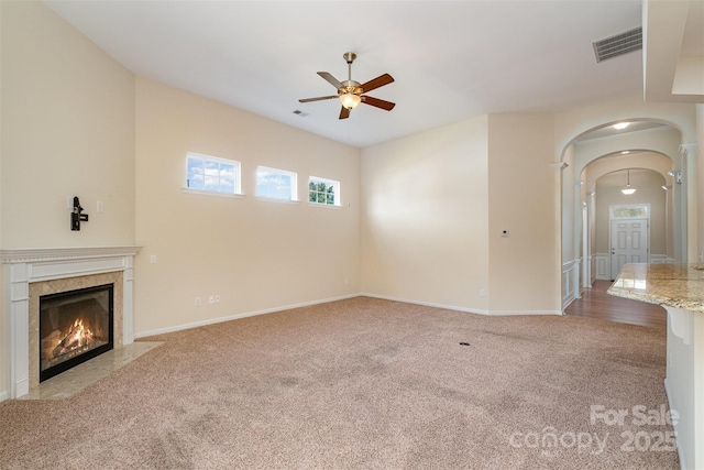 unfurnished living room with ceiling fan, light carpet, and a high end fireplace