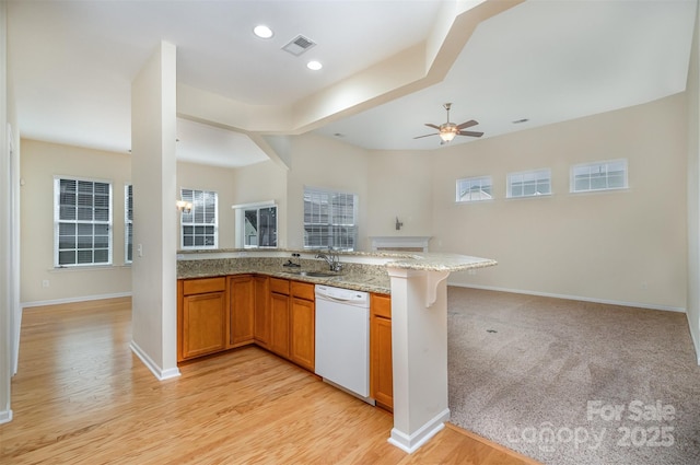 kitchen with sink, dishwasher, ceiling fan, light stone counters, and kitchen peninsula