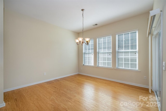 spare room featuring a chandelier and light hardwood / wood-style floors